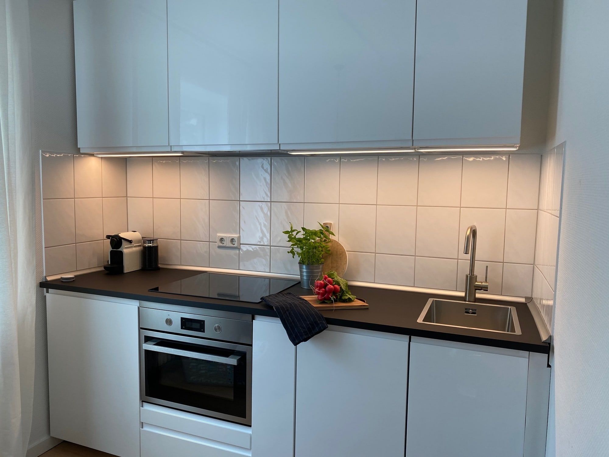 Weiße moderne Küche mit Backofen, Spüle und Kaffeemaschine