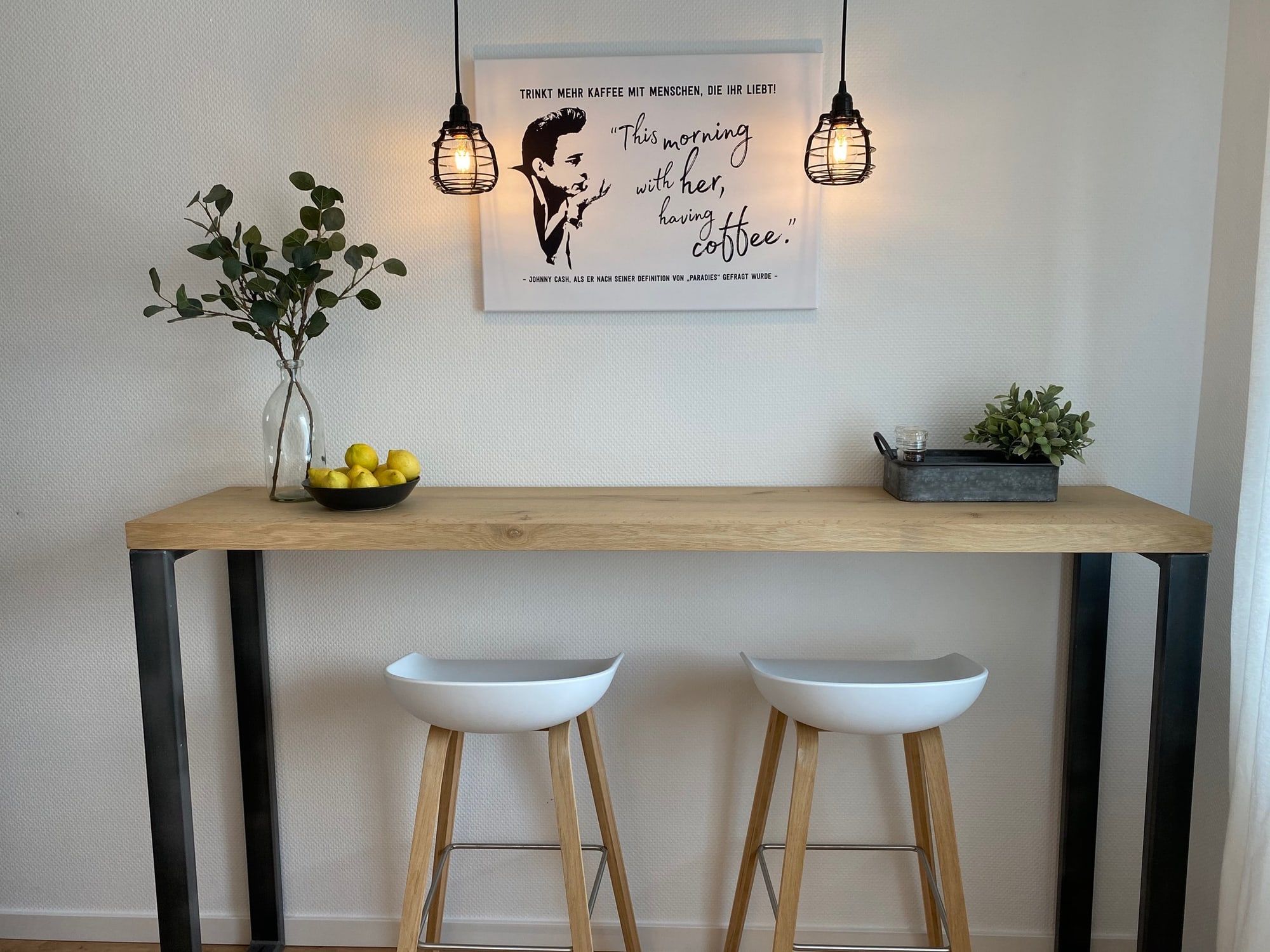 Modern breakfast bar with two white stools and a coffee-themed wall art