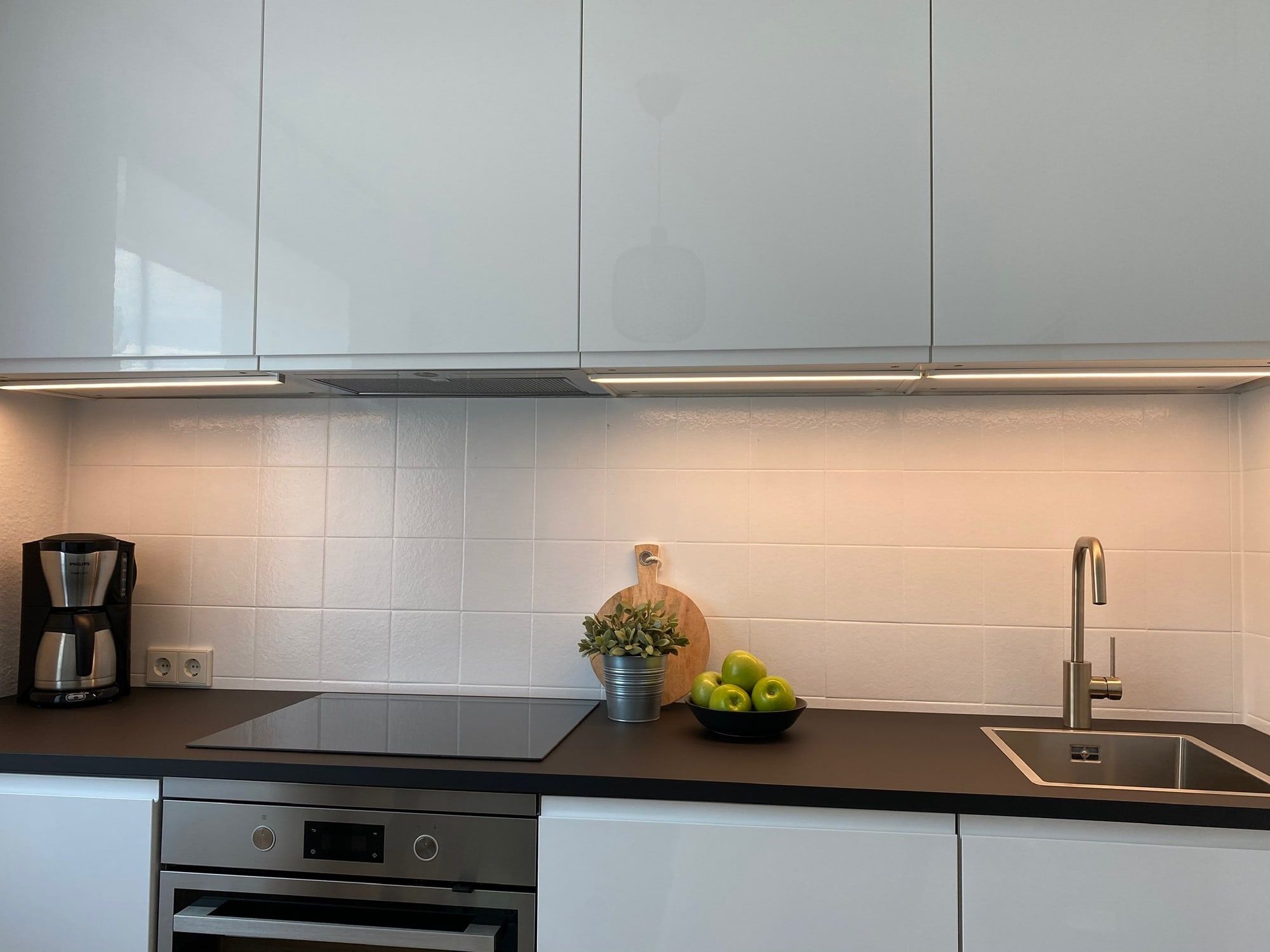 Moderne Küche mit weißen Schränken, schwarzer Arbeitsplatte und Kaffeemaschine