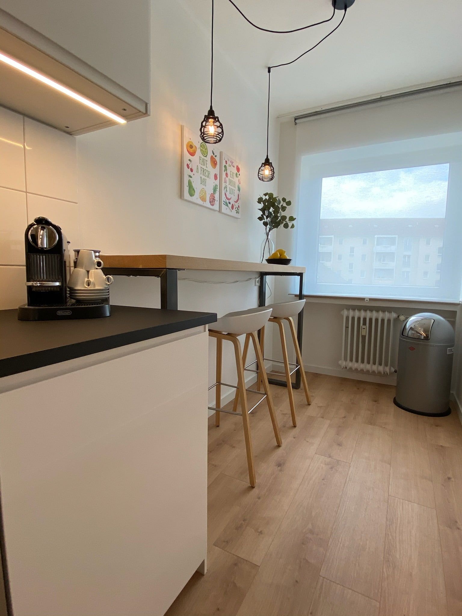 Bright modern kitchen with bar stools and two hanging lamps