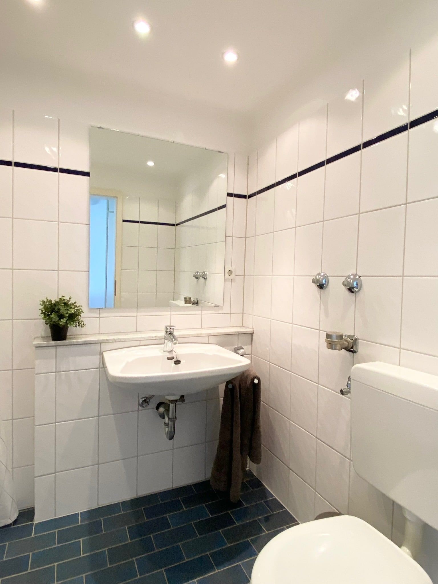 Small bathroom with white tiled walls and blue floor