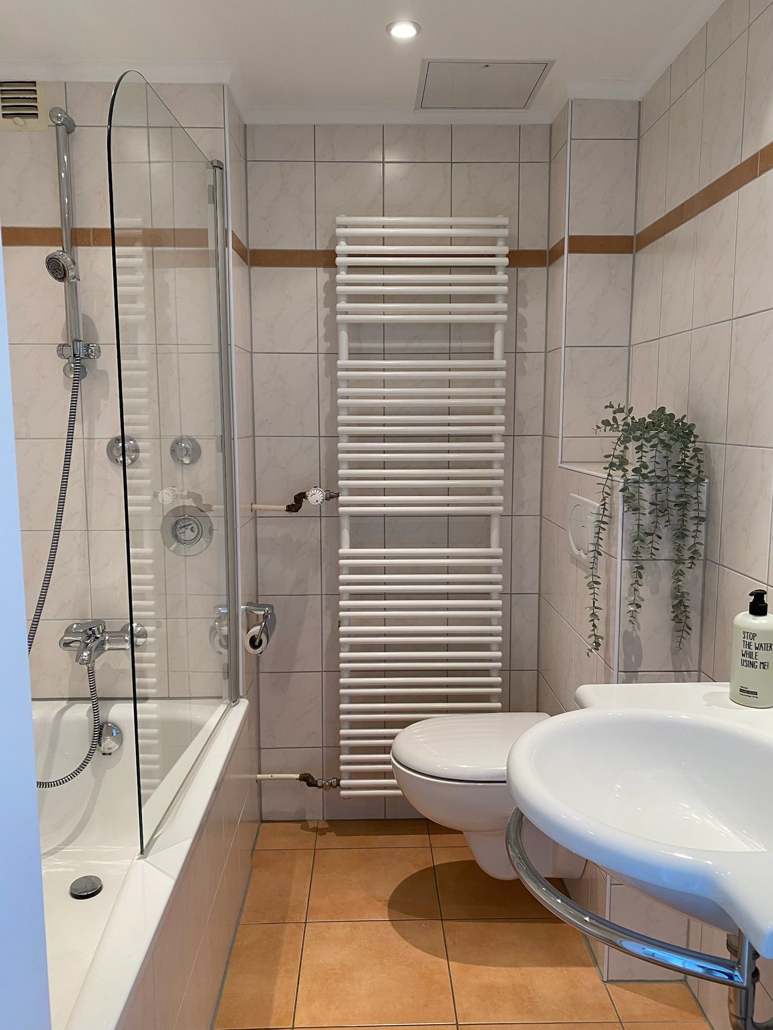Kleines Badezimmer mit Badewanne, Waschbecken und Handtuchheizkörper