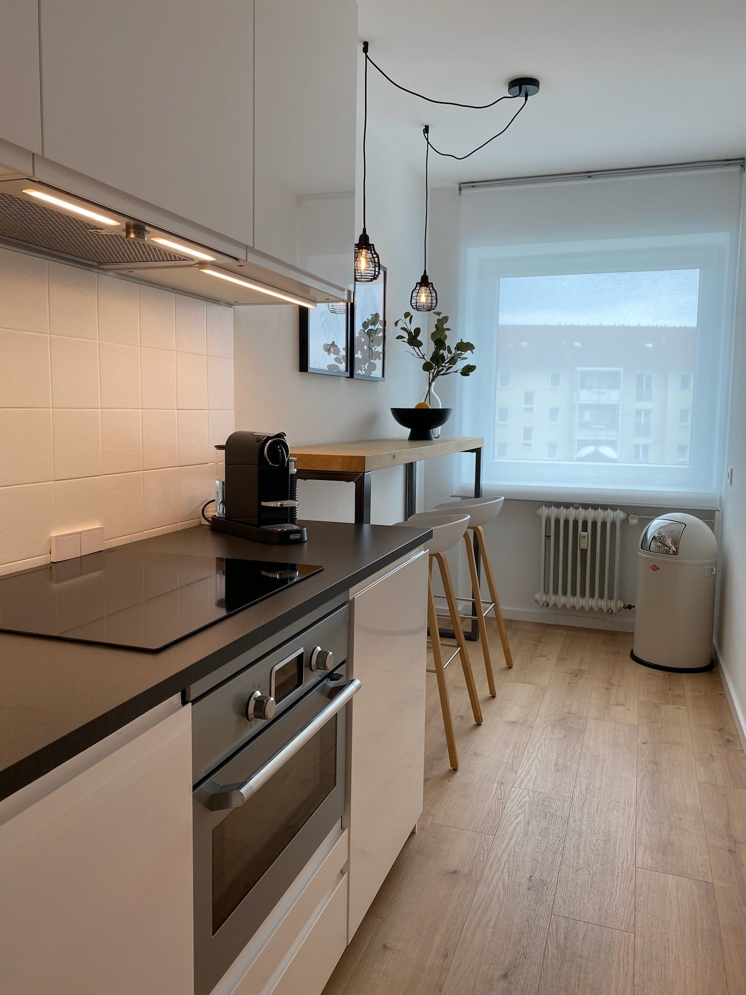 Helle moderne Küche mit Kochfeld, Kaffeemaschine und Bartresen mit zwei Hockern