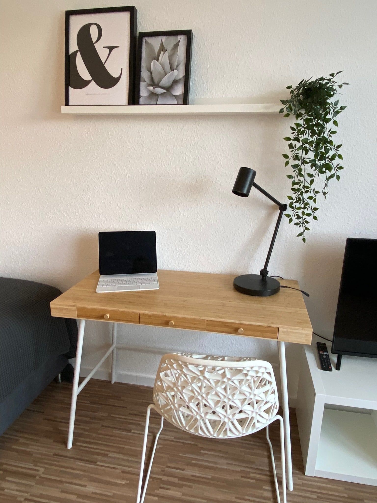 Ein Schreibtisch mit Laptop, Lampe und dekorativen Bildern an der Wand.
